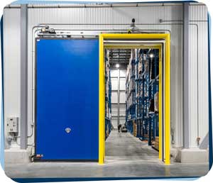 A look through the man door into the TransCold freezer facility as a worker performs their job in the background